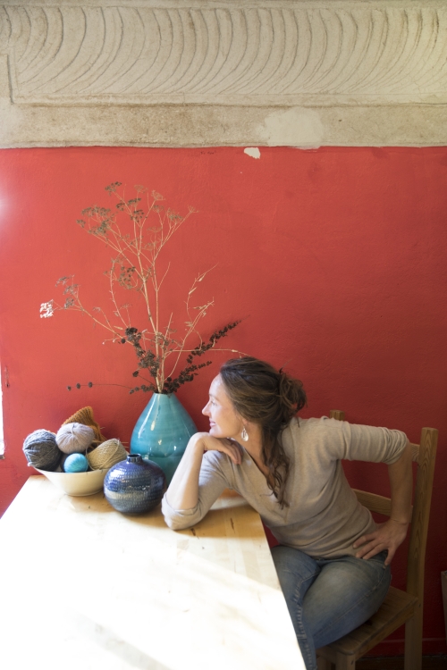 Massey Burke sitting at a table in her home, against an orange background